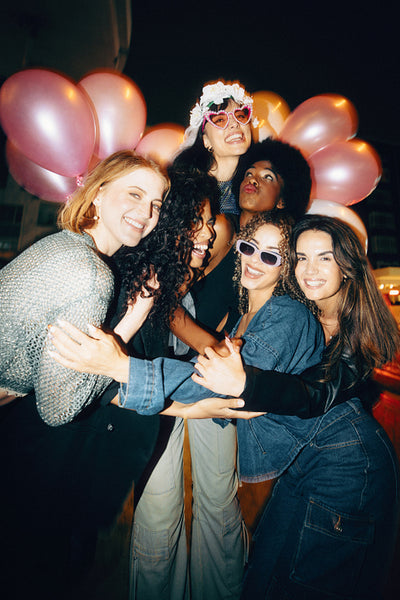 Group of friends celebrating with balloons and party accessories at night