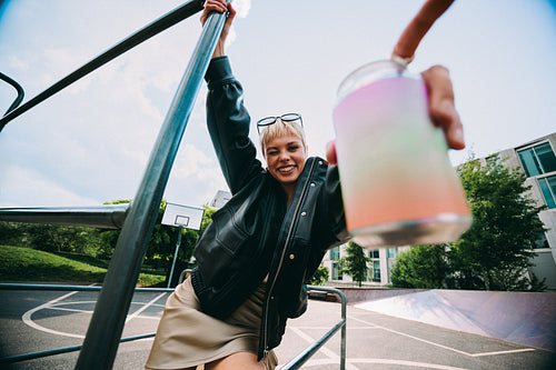 Winking woman holds playground bars with a beverage