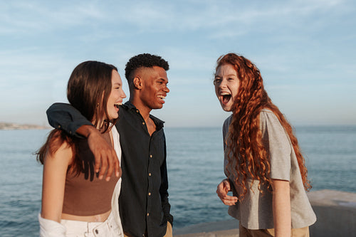 Carefree friends sharing a hilarious moment next to the sea