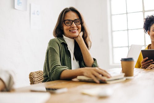 Happy business woman sitting in a boardroom, having a meeting with her colleagues