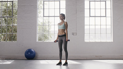 Woman exercising with dumbbells at fitness studio