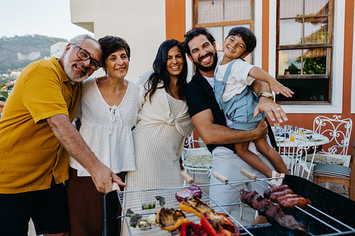 Smiling family enjoying a Brazilian churrasco barbecue together outdoors