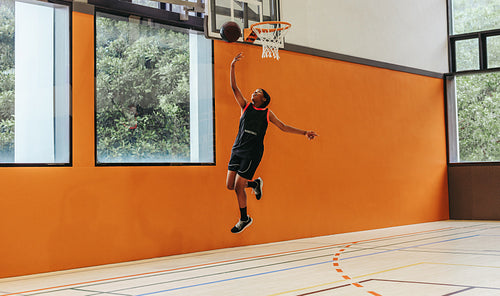 Young athlete dunking a basketball during an indoor training session