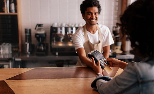 Young woman paying by credit card at cafe