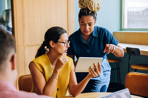 Two businesswomen discussing ideas using a digital tablet during a meeting