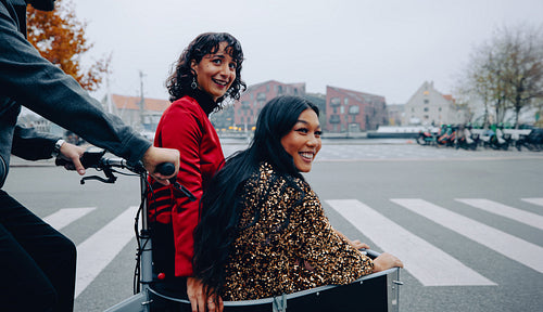 Friends enjoying a fun ride in a cargo bike through an urban street