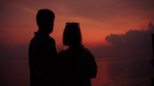 Mature couple watching the beautiful sunset over the ocean