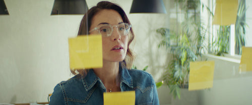 Businesswoman writing on sticky notes in a modern office