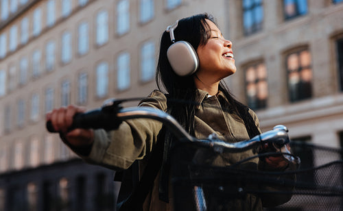 Woman riding bicycle smiling while wearing headphones
