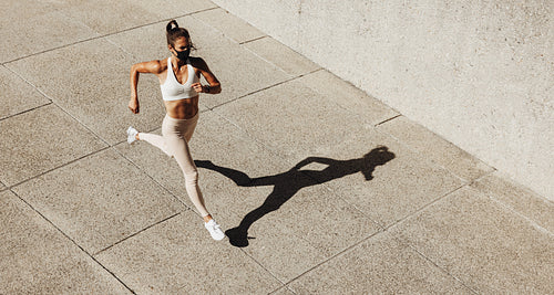 Woman wearing face mask sprinting outdoors