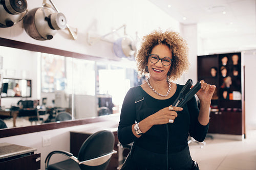 Female hairdresser at the salon holding a hair straightener