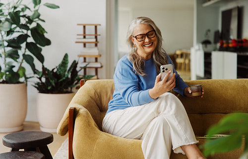Senior reads a smartphone in an armchair at home