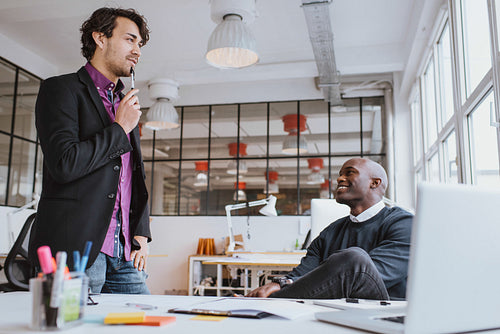 Two young office workers discussing work in office