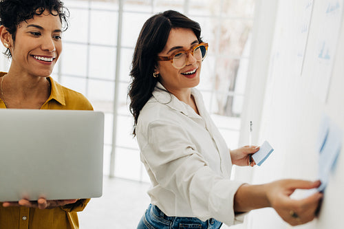 Happy business women creating a to do list using sticky notes