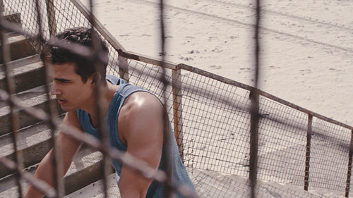 Muscular man taking a break after workout on beach