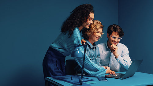 Group of colleagues collaborating on a laptop in colorful office