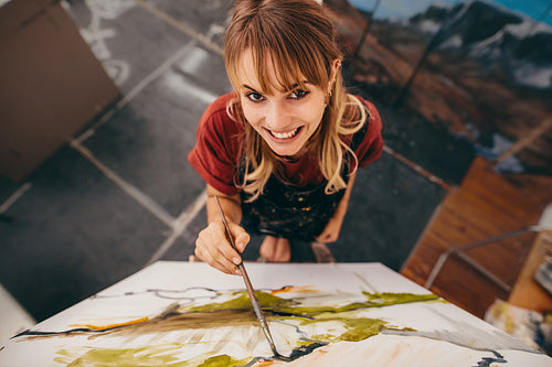 Smiling woman painter drawing on canvas