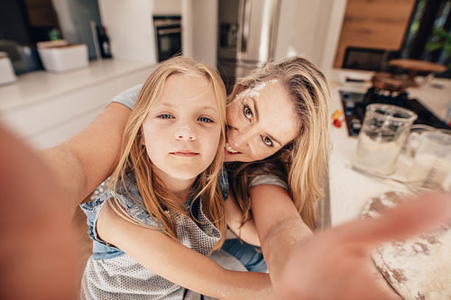 Happy woman and girl taking a selfie in kitchen