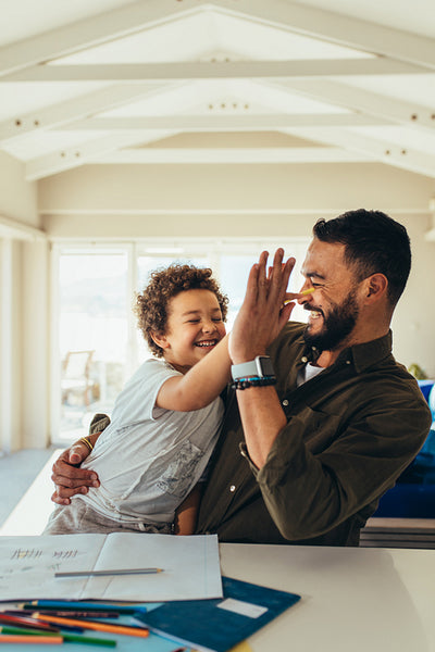 Father and son sitting at the table giving high five