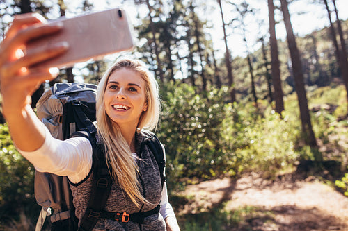 Woman hiker taking photograph in forest