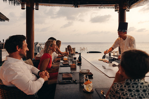 Family enjoy a teppanyaki dining experience at a seaside restaurant at sunset