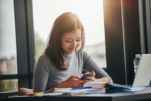 Asian girl using mobile phone at library