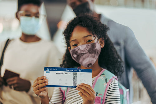 Girl showing boarding pass with family at airport