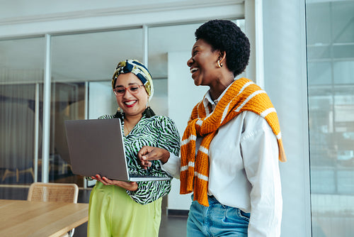 Friendly colleagues collaborating with a laptop in a modern agency office