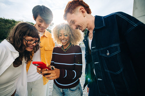 Friends smiling together while looking at phone