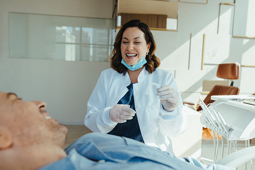 Dentist explains oral care to reclining patient in chair