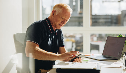 Senior businessman using mobile phone at work