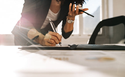 Businesswoman making notes standing at her desk in office
