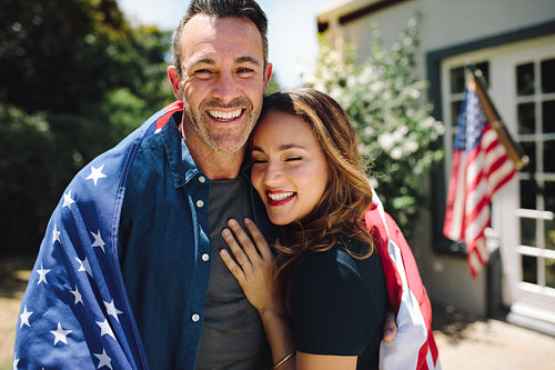 Couple standing together carrying the american flag
