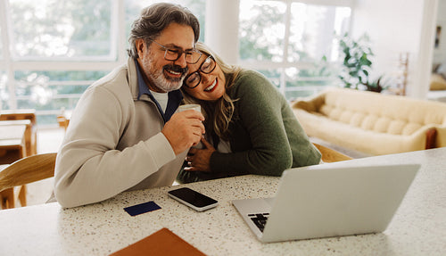 Senior couple use laptop together at home