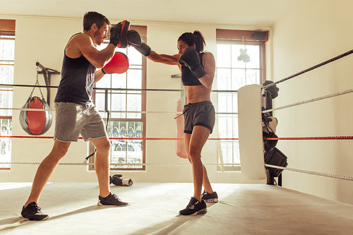 Trainer helping a female boxer with reverse punches