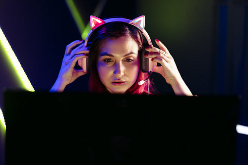 Female night gamer looking at her computer screen, fully immersed in her video game
