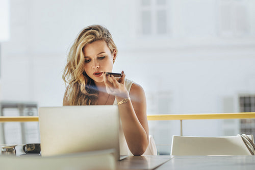 Woman at cafe with laptop making phone call