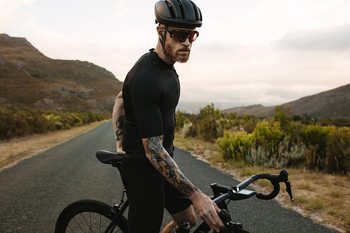 Cyclist with bicycle standing outdoors