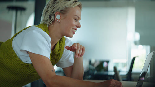 Woman talks on a laptop video call with a headset at a desk