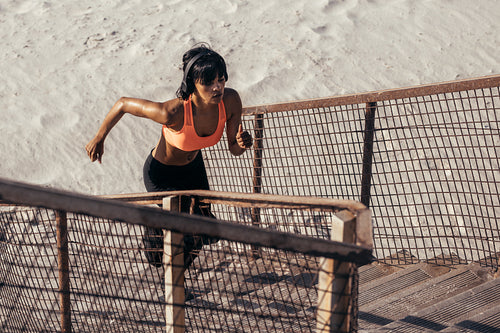 Runner climbing steps on the beach