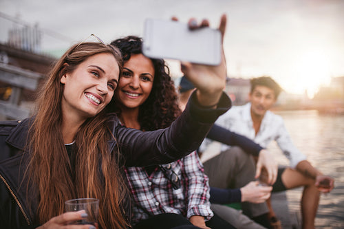 Young female friends taking selfie on the lake