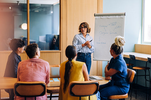 Woman presenting business strategies to a diverse group in a discussion