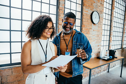 Happy colleagues discussing a project in an industrial style office environment with smiles and coffee