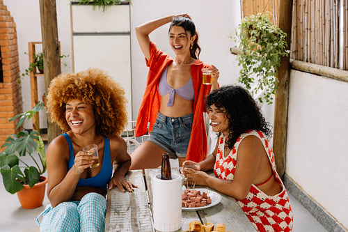 Three Brazilian friends enjoying snacks and drinks while laughing outdoors