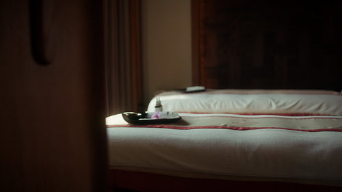 A spa therapist prepares a luxurious treatment room for a relaxing massage session