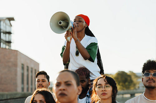 Group of protestors with a woman speaking through a megaphone outdoors