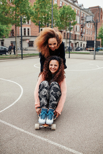 Hipster girls riding on skateboards along the road
