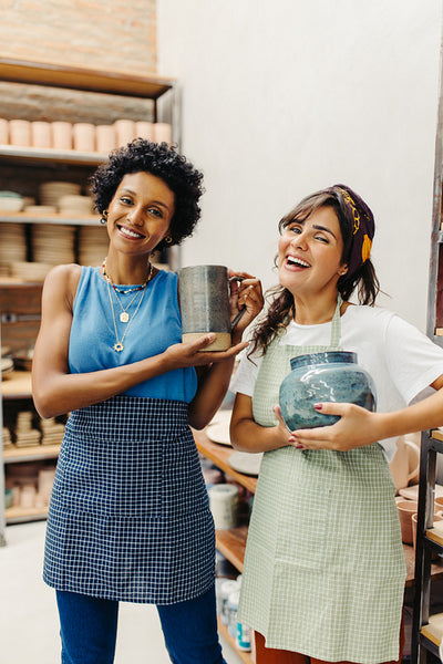 Successful female potters holding their handmade ceramic products