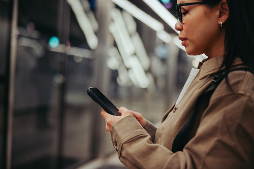 Commuter using smartphone on subway platform during commute
