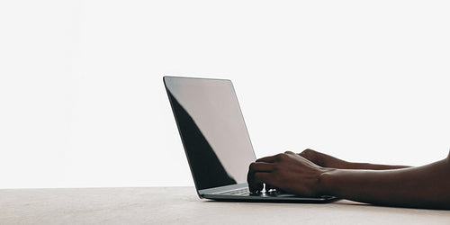 Hands typing on a laptop computer on a minimalistic desk surface